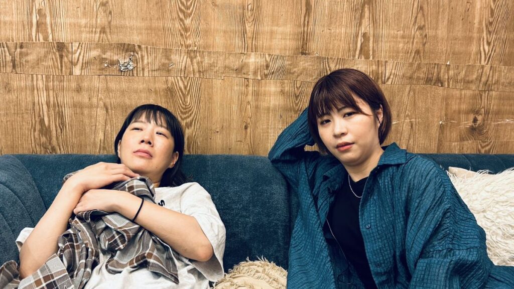 不機嫌そうな顔でソファに座るAマッソ村上と加納