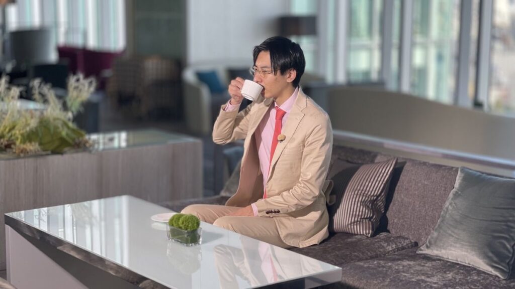 マグカップ片手に飲み物を飲む永見さん